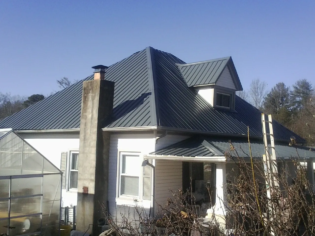 Dark blue standing seam metal roof on a white farmhouse with dormer — Slate & Tile Roof Repair by Roofing Brothers in Meigs
