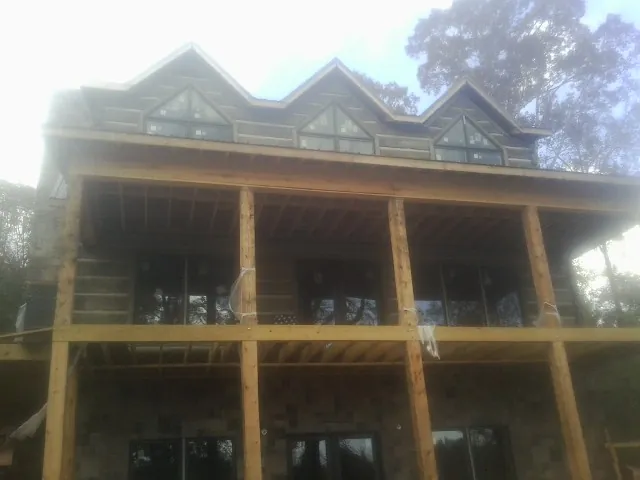 Dormers and porch framing on a large log home under construction — Roof Coating work by our crew in Meigs