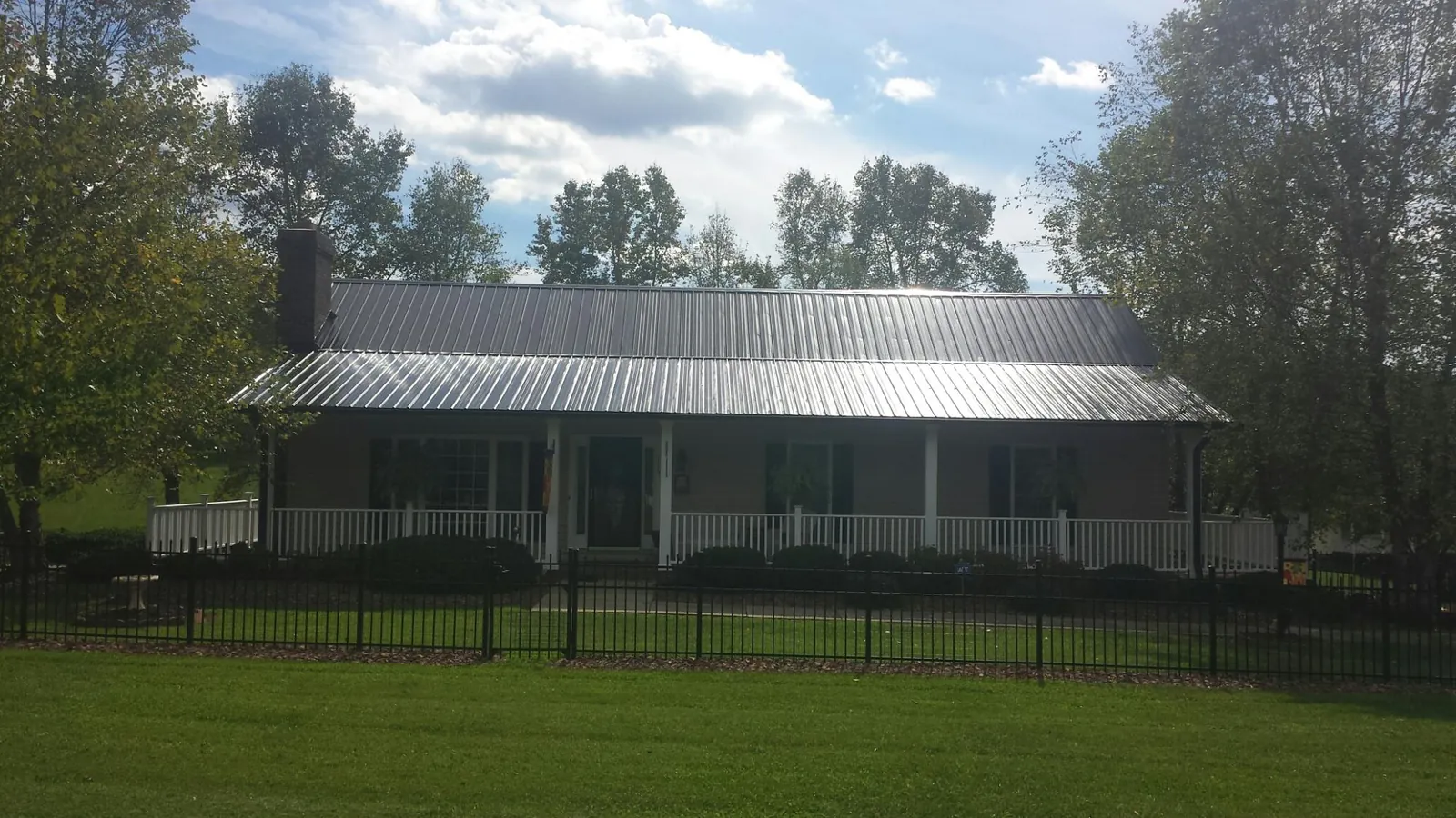 Gray metal roof on a brick ranch with a full width front porch — Gutter Guard Installation work by our crew in Meigs