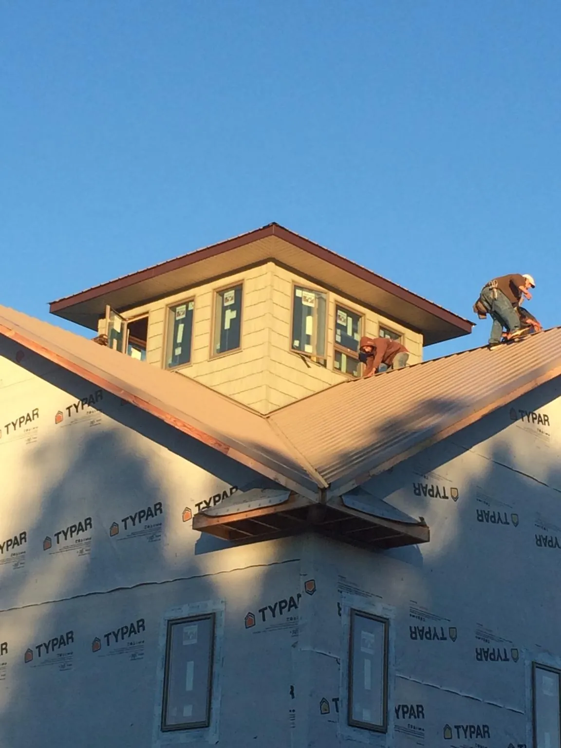 Roofers working around a rooftop cupola on a new metal roof at sunset — Roof Waterproofing in Meigs by Roofing Brothers
